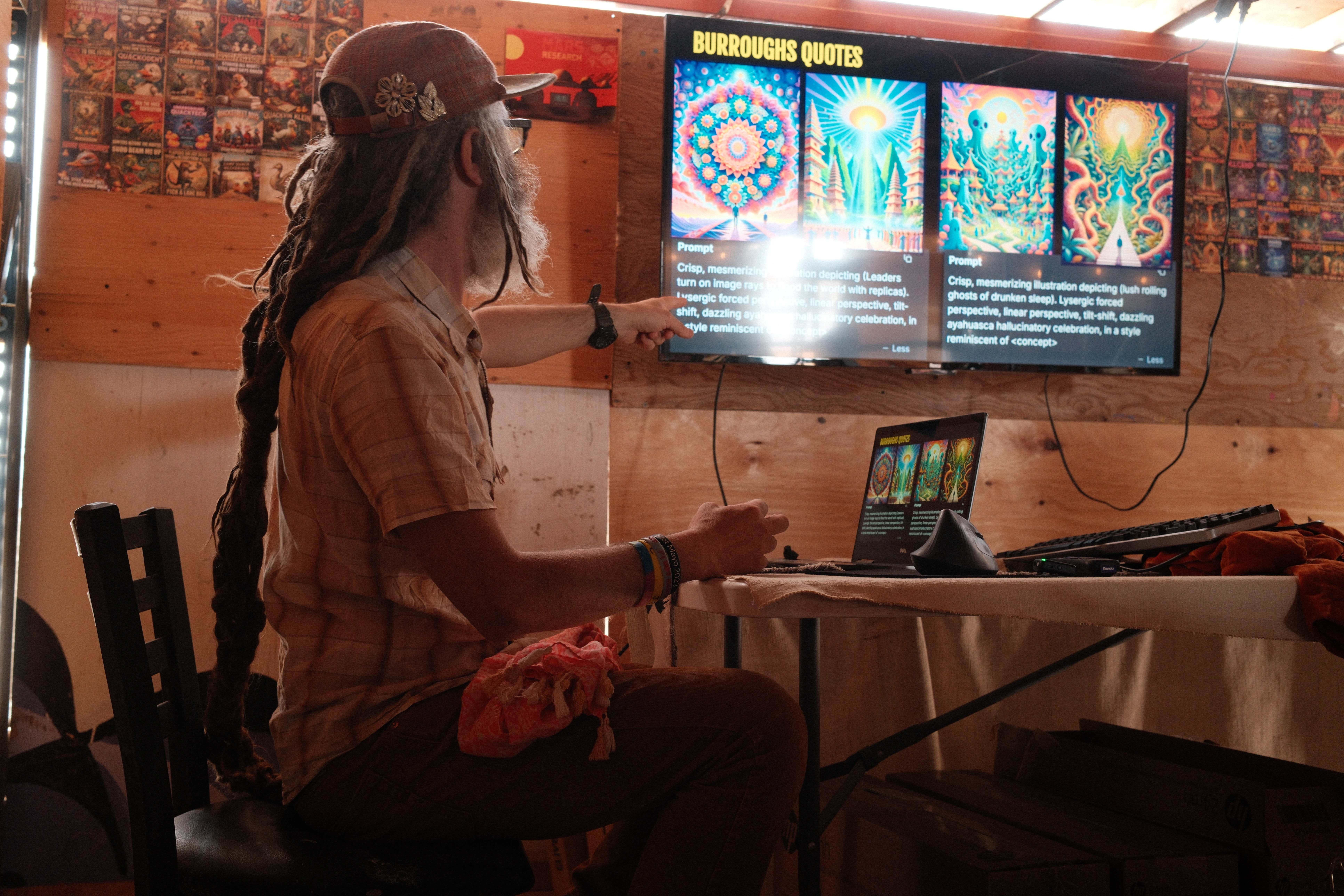 A person with long dreadlocks points at a large screen displaying colorful AI-generated art.