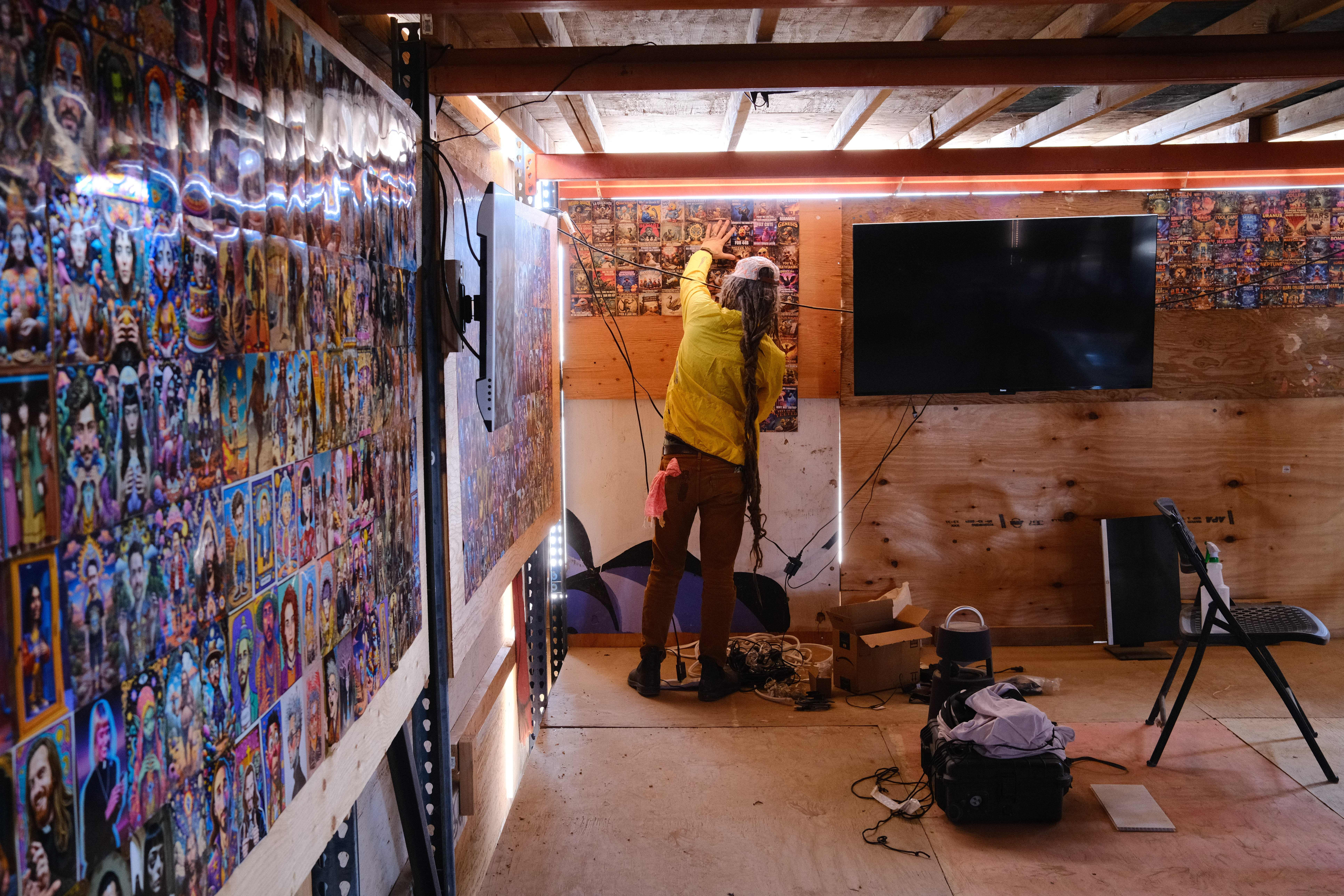 A person curating a wall of printed AI-generated images for the gallery.