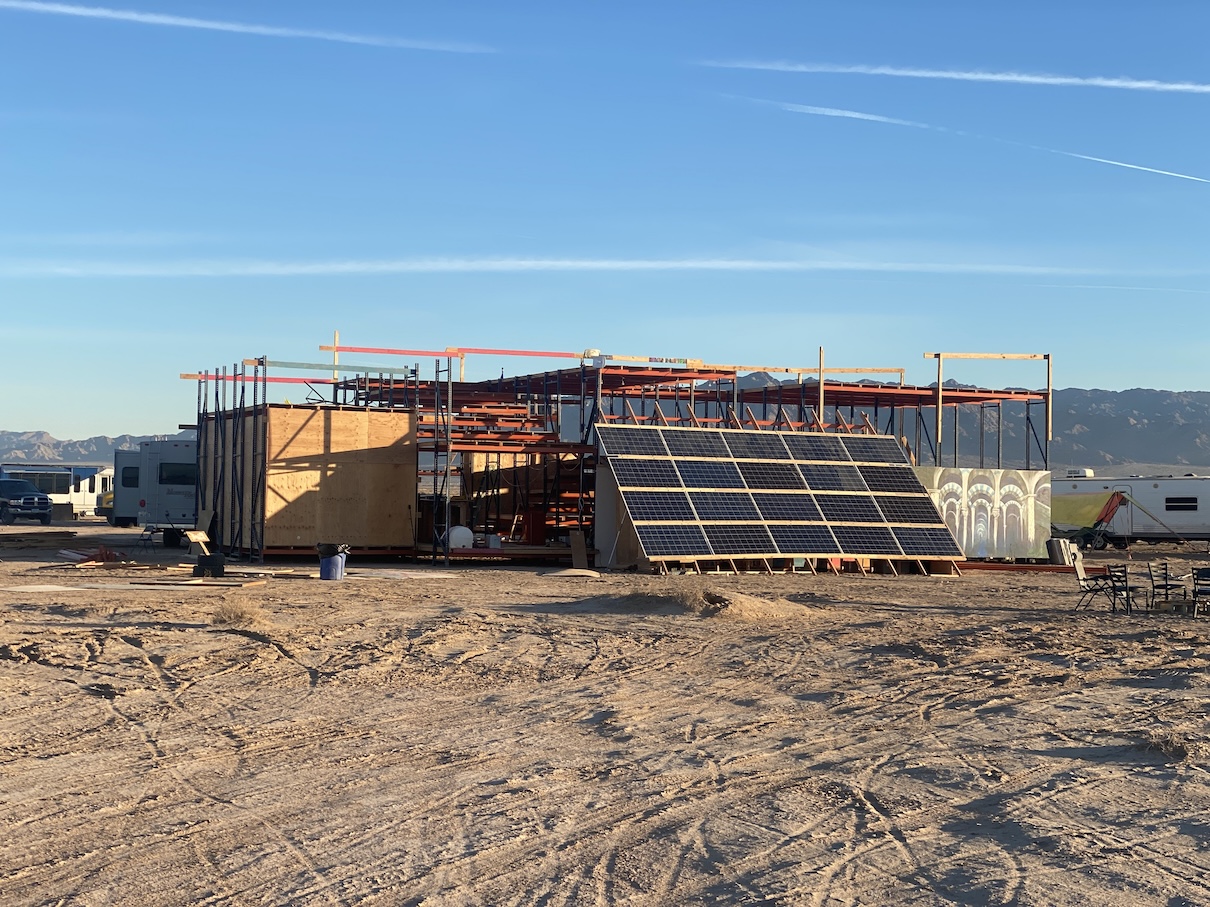 A large structure under construction with solar panels in the desert.