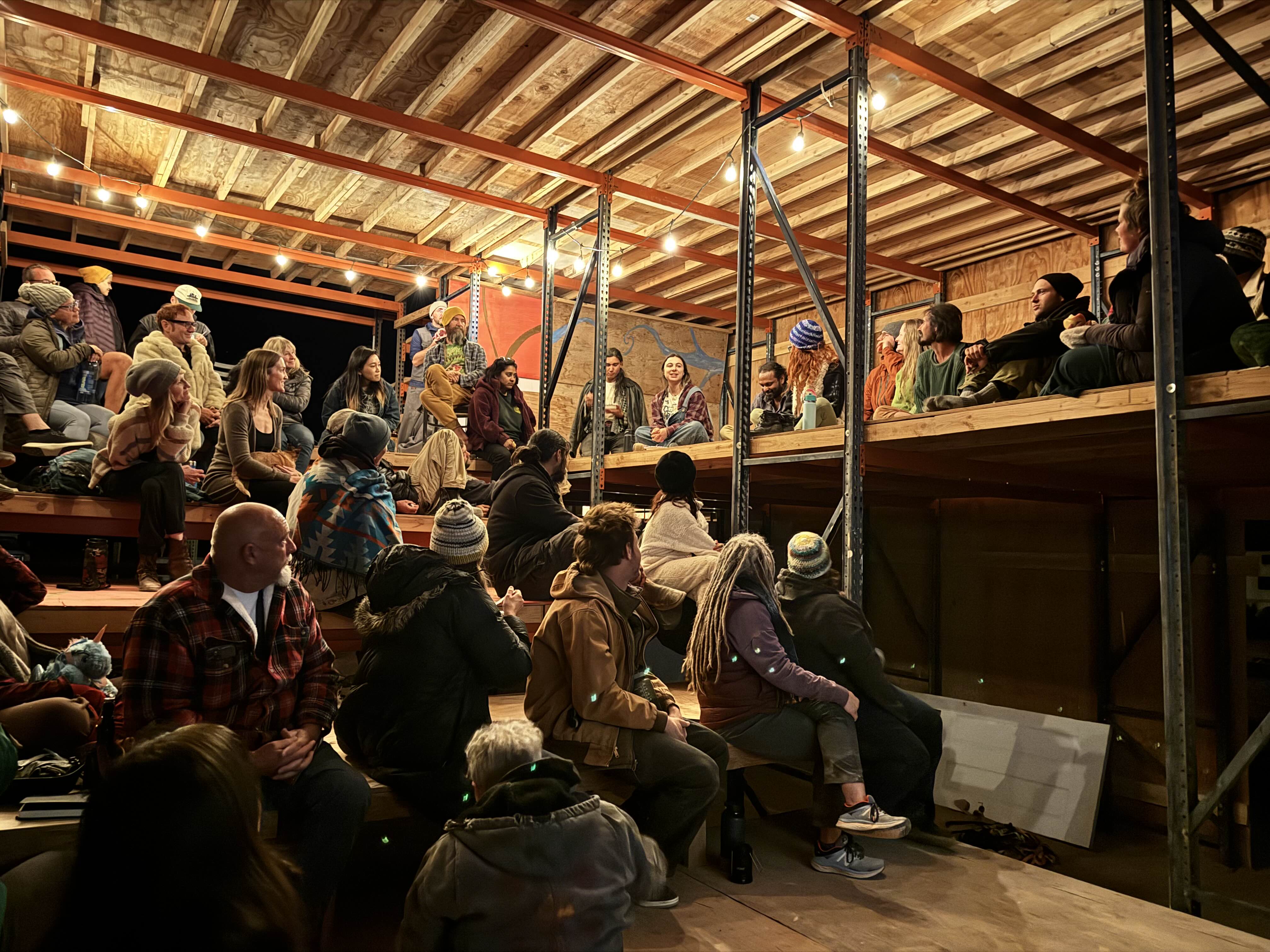 A community gathering for a talk inside a structure at night.